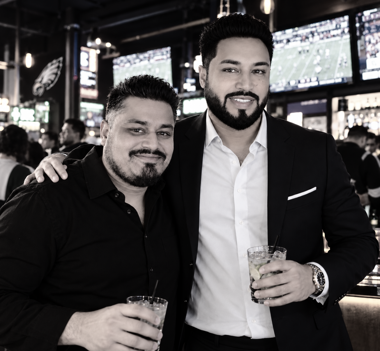 Mak and Bhushan standing together holding cocktails