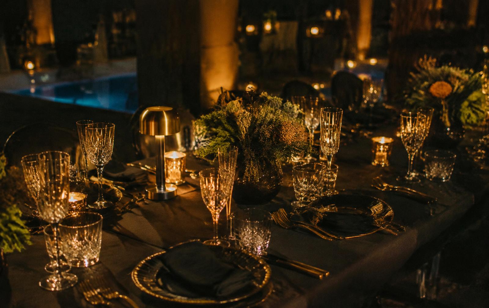 Candlelit dinner table set in black and gold